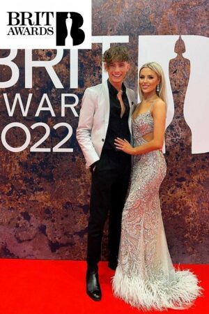 eden mcallister at the brit awards wearing a Silver and nude tight fitting dress with feathered detailing at the hem and cut-outs at the waist.