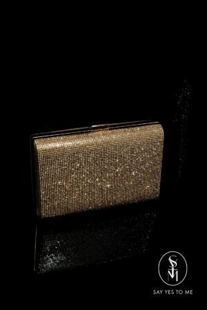 'CLASSIC' in gold is a rectangular clutch that exudes glamour with its countless shimmering gemstones. It offers sophistication to any outfit by catching the light from every angle.